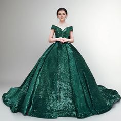 a woman in a green ball gown posing for the camera with her hands on her hips