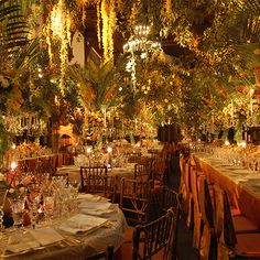 the tables are set for an event with candles and flowers hanging from the ceiling above them