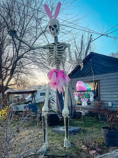 a skeleton is standing in the yard with pink tutues on it's feet