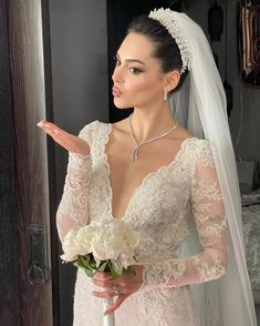 a woman wearing a wedding dress and holding a bouquet in her hand while standing next to a doorway