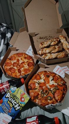 two pizzas in boxes with pepperoni and other toppings next to soda bottles