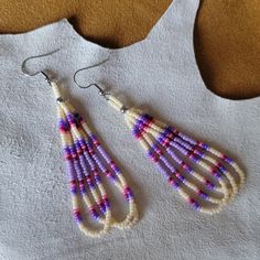 a pair of beaded earrings sitting on top of a white shirt