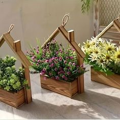 three wooden planters with flowers in them on a table