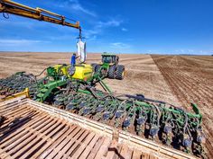 a tractor is parked in the middle of a field with other equipment on top of it