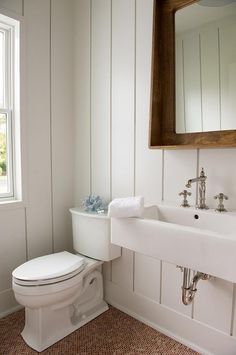 a white toilet sitting next to a sink in a bathroom under a large framed mirror