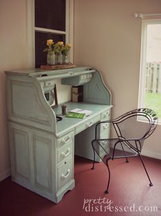 an old desk and chair are in the corner of a room with a large window