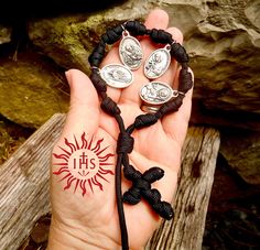 a person holding some kind of bracelet with charms on it's wrist and two other items in their hand