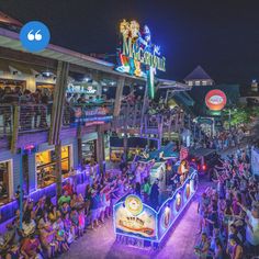 a crowd of people standing in front of a building with neon signs on the side