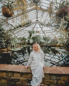 a woman sitting on a ledge in a greenhouse