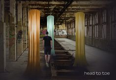 a person standing in an abandoned building with yellow and green curtains hanging from the ceiling