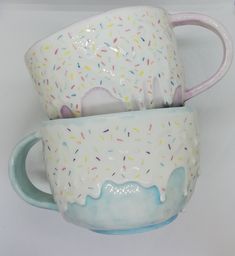 two ceramic mugs with sprinkles on them