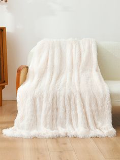 a white couch sitting next to a wooden table on top of a hard wood floor