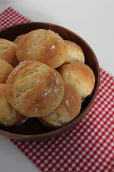 a bowl filled with rolls sitting on top of a red and white checkered table cloth