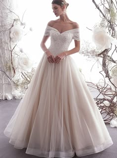 a woman in a wedding dress standing next to a floral arch with flowers on it