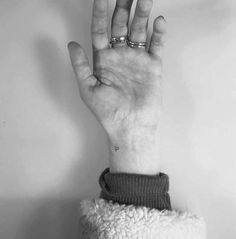 black and white photograph of a person's hand with two rings on their fingers