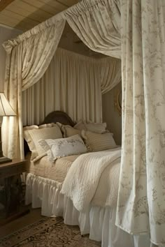 a canopy bed with curtains and pillows on top of it in a bedroom next to a dresser