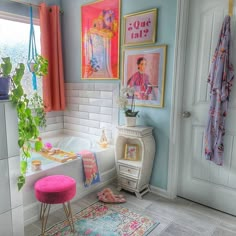 a bathroom with pictures on the wall and a pink stool in front of a bathtub