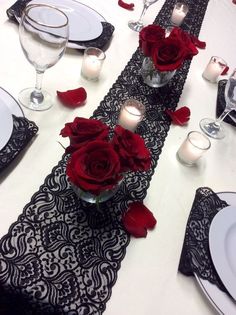 the table is set with red roses and candles