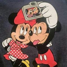 mickey and minnie mouse kissing each other with a camera on their head in front of them