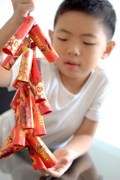 a young boy is holding up some candy