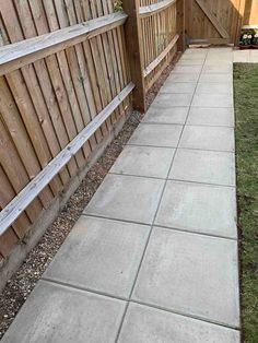 a cement sidewalk next to a wooden fence