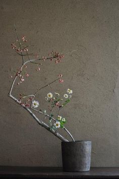 a vase filled with flowers sitting on top of a wooden table next to a wall