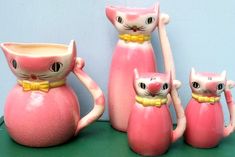 a group of pink ceramic cat figurines sitting on top of a green table