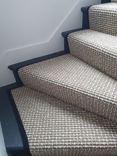 a carpeted stair case next to a white wall