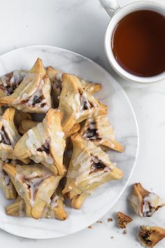 a white plate topped with pastries next to a cup of tea