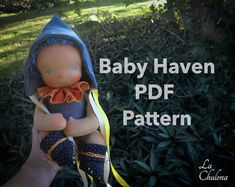 a person holding a doll in their hand with the text baby haven pattern on it