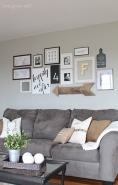 a living room with gray couches and pictures on the wall above them in various frames