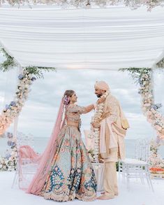 a bride and groom standing in front of an outdoor wedding ceremony setup with flowers on the altar