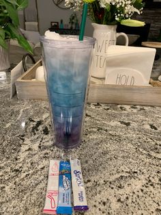 a blue drink sitting on top of a counter next to a vase filled with flowers