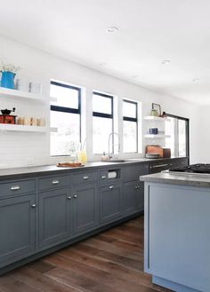 a kitchen with gray cabinets and wooden floors