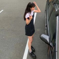 a woman standing next to a car on the side of the road with her hand in her hair