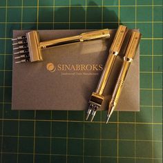 two golden fountain pens sitting on top of a piece of paper next to each other