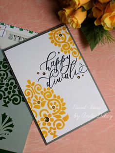 a close up of a card on a table with yellow flowers and a pen next to it