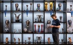 a man holding a soccer ball in front of a display case filled with trophy trophies