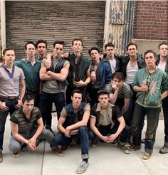 a group of young men standing next to each other in front of a garage door