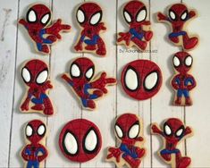 spiderman cookies decorated with royal icing are arranged on a white wooden table, ready to be eaten