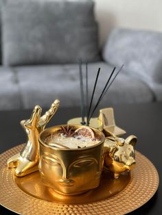 a golden cup with candles in it sitting on a gold plate next to a couch