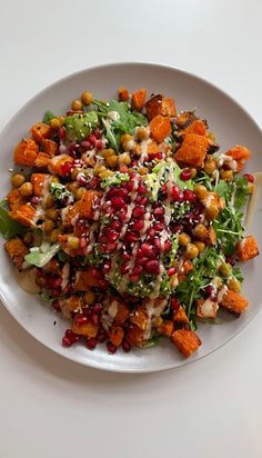 a white plate topped with a salad covered in pomegranate and other toppings