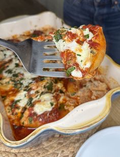 a piece of pizza is being lifted from a casserole dish with a fork