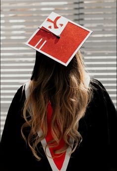 a woman wearing a graduation cap with a red and white sign on it's head