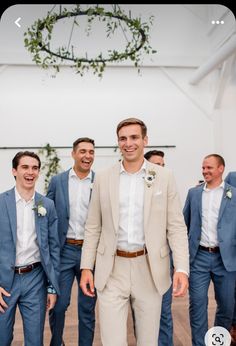 a group of men standing next to each other wearing suits and smiling at the camera