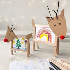 two wooden reindeers are standing next to each other in front of an easel