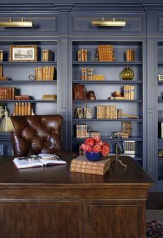 a leather chair sitting in front of a desk with bookshelves on the wall