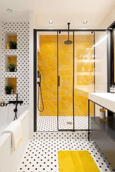 a bathroom with yellow and black decor on the walls, white tile flooring and a walk in shower