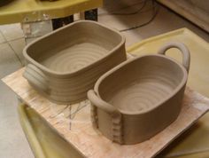 two white bowls sitting on top of a wooden table