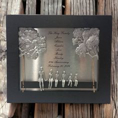 a couple of figurines are in a shadow box with trees and people holding hands